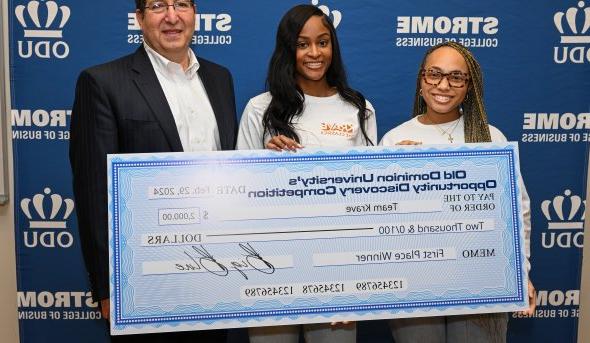 Three individuals pose with a large check